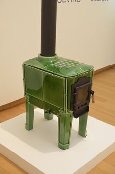 a green stove sitting on top of a white platform in front of a sign that says giving design