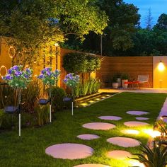 an outdoor garden at night with lights on the grass and stepping stones in the ground