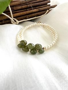 Elevate your style with this exquisite double wrap bracelet, featuring one long strand of lustrous freshwater pearls accented by stunning olive green Vesuvianite briolettes. This unique combination of creamy pearls and vibrant Vesuvianite gemstones adds a touch of sophistication and elegance to any outfit, making it the perfect accessory for both everyday wear and special occasions. The bracelet is meticulously handcrafted with 14k gold-filled components, offering a luxurious finish that's tarni Elegant Adjustable Wrap Bracelet With Natural Stones, Elegant Wrap Bracelet With Round Natural Stones, Elegant Wrap Bracelet With Natural Stones As A Gift, Elegant Double Strand Natural Stones Bracelets, Elegant Wrap Bracelet With Natural Stones, Elegant Green Hand Wrapped Bracelets, Bracelet For Women Gold, Double Wrap Bracelet, Freshwater Pearl Bracelet