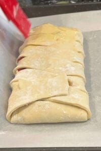 an uncooked tortilla sitting on top of a metal counter next to a red container