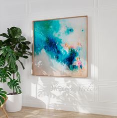 a painting hanging on the wall next to a potted plant in a white room