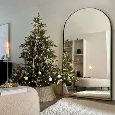 a living room with a christmas tree in the corner and a mirror on the wall