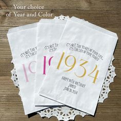 four personalized wedding napkins with the year and color printed on them, sitting on a doily