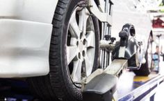 a car being worked on by a mechanic at a service station with other cars in the background