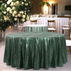 the table is covered with green sequins and has white flowers in vases