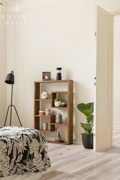 a bedroom with white walls and wooden flooring has a plant in the corner on the bed