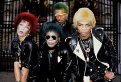 the group of punk rockers posing for a photo in front of an iron gate