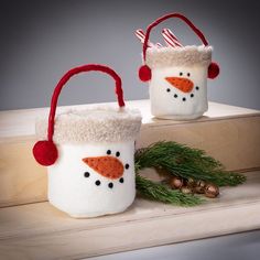 two snowmen in christmas hats sitting next to each other on a wooden shelf with pine branches