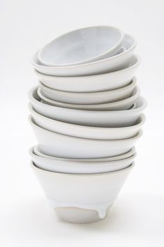 a stack of white bowls sitting on top of each other in front of a white background