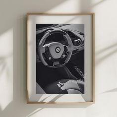 a black and white photo of a sports car steering wheel with the center console visible