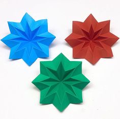 three different colored origami flowers sitting next to each other