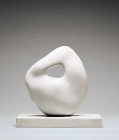 a white sculpture sitting on top of a marble block in front of a gray background