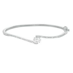 Turn heads with this eye-catching bangle bracelet. Fashioned in sterling silver, this stunning design showcases a 7.0 x 5.0mm oval-shaped lab-created shimmering white sapphire embraced by bypassing beaded ribbons. Petite diamonds lend further sparkle to the look. Radiant with 1/20 ct. t.w. of diamonds and a brilliant buffed lustre, this 7.0-inch bracelet secures with a tongue and groove clasp. Formal Oval Bangle With Diamond Accents, Classic Oval Bangle With Diamond Accents, Oval Bangle With Diamond Accents In Fine Jewelry Style, White Gold Oval Bangle For Formal Occasions, Oval Jubilee Bracelet For Anniversary, Oval Diamond White Cubic Zirconia Bracelet, Oval Cubic Zirconia Bracelet In Diamond White, Elegant Oval Bangle For Gifts, Oval Adjustable Bangle For Formal Occasions