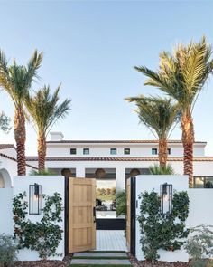 a white house with palm trees in the front yard and an entry way leading to it