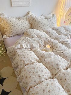 a bed with white sheets and pillows on top of it next to a vase filled with flowers