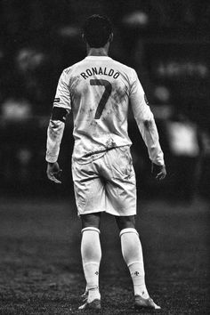 a man standing on top of a soccer field wearing a uniform and holding a ball