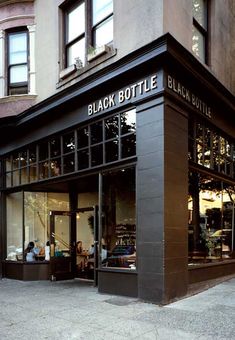 a black bottle store front with people sitting outside