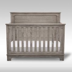 a wooden crib with white sheets on it