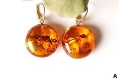 The earrings of Baltic amber in rich honey colour will not betray your expectations. It is one of the most popular colours of Baltic amber.  These massive, elegant, sophistically sparkling earrings with a spangle inside are an irresistible piece of jewellery that you will love wearing every day. It is a genuine, natural and unique piece of jewellery created by nature, so you will feel special on every occasion. Delight yourself or your loved one with a little miracle from nature.  EARRINGS A Earrings length with clasp: 4.8 cm. / 1.88 inch. Weight: 14.9 g. / 0.52 oz Color: cognac, golden Natural Baltic amber 925 sterling silver gold plated EARRINGS B Earrings length: 4.6 cm. / 1.81 inch. Weight: 12.2 g. / 0.43 oz Color: cognac, orange, gold Natural Baltic amber 925 sterling silver gold plat Amber Round Pierced Earrings, Elegant Handmade Tortoiseshell Jewelry, Brown Baltic Amber Round Jewelry, Handmade Baltic Amber Orange Jewelry, Brown Baltic Amber Jewelry, Round Brown Baltic Amber Jewelry, Handmade Orange Earrings For Formal Occasions, Amber Dangle Earrings In Baltic Amber, Orange Baltic Amber Round Jewelry