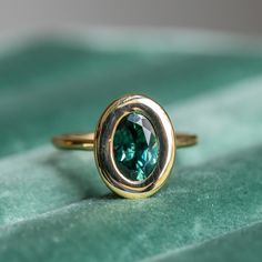 a close up of a ring with a green stone in the center on a velvet surface