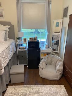 a bedroom with a bed, dresser and chair in it's corner area next to a window