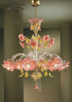 a chandelier with pink flowers hanging from it's centerpiece in a room