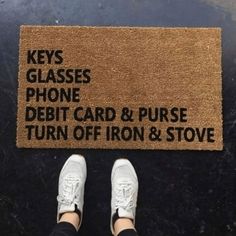 a person standing in front of a door mat that says keys glasses phone debt card and purse turn off iron & stove