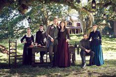 a group of people standing next to each other in front of a table under a tree