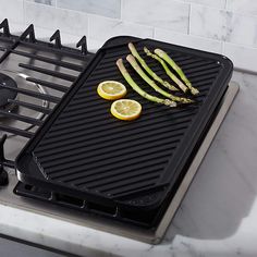 asparagus and lemons are being cooked on the griddle in the kitchen