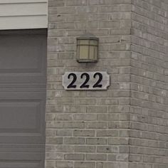 a house number sign on the side of a brick building next to a garage door