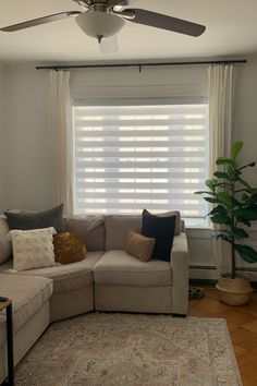 a living room with a sectional couch, rug and ceiling fan in the middle of it