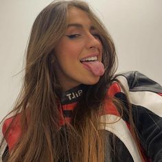 a woman sticking her tongue out while wearing a leather jacket