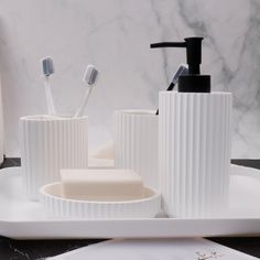 three toothbrushes and two soap dispensers sitting on a white tray