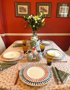 the table is set with plates, cups and vases