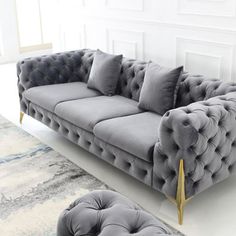 a grey couch and ottoman in a room with white walls, carpet and rugs