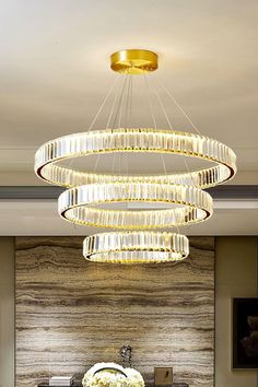 a modern chandelier hanging from the ceiling above a table with flowers on it