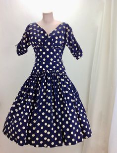 1950's Navy Blue & Creamy White Polka-Dot Drop-Waist Dress. Quality cotton fabric with a fitted bodice and a drop waist, a full gathered skirt, and a neckline that V'S in the front as well as the back. The drop waist is 3 inches lower on the sides than in the front.. which adds interest and wow factor to the silhouette. Such a beautiful dress!! There is a metal zipper that runs down the back of this dress for that perfect tailored hourglass fit. This garment is in EXCELLENT VINTAGE CONDITION Vintage Dress With Full Skirt And Fitted Top, Vintage Fitted Dress With Full Skirt, Fitted Polka Dot Vintage Dress, Fitted Full Skirt Vintage Dress For Vintage Fashion, Fitted Vintage Dress With Full Skirt For Vintage Fashion, Retro Dress With Lined Fitted Waist, Fitted Full Skirt Vintage Dress, Retro Fitted Dress With Full Skirt, Fitted 1950s Polka Dot Dresses