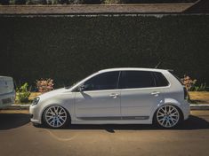 a white car parked in front of a hedge