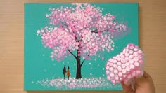 someone is painting a tree with pink flowers