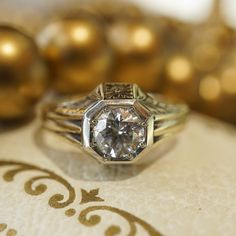 This Retro era engagement ring features a .71 carat Round Brilliant cut diamond and orange blossom engravings in 14 karat yellow gold. The sparkling near colorless diamond is bead set in the center of an octagon mounting. The sharp lines and romantic floral engravings give the geometric engagement ring an artistic look. From the profile, orange blossom engravings decorate the gallery rail, finished on a polished 14 karat yellow gold band. PRIMARY STONE Stone: Genuine Natural Diamond Measurements Classic Gold Platinum Wedding Ring, Classic Gold Platinum Wedding Jewelry, Heirloom White Diamond Ring With Rose Cut Diamonds, Heirloom White Rose Cut Diamond Ring, Vintage White Diamond Ring With Rose Cut, Heirloom Diamond Solitaire Jewelry, Heirloom Solitaire Diamond Wedding Ring, Heirloom Round Single Diamond Wedding Ring, White Brilliant Cut Art Deco Jewelry