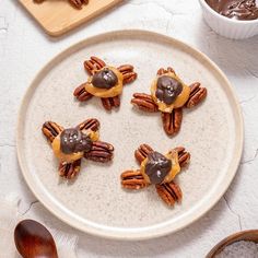 some pecans are sitting on a plate with chocolate sauce and candies in the shape of cats