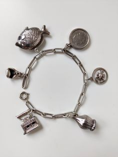 Prachtige vintage design armband in zeer goede staat met unieke bedeltjes. Staat prachtig om de pols met en zet een uniek tijdsbeeld neer. Goed werkende sluiting met een vaste veiligheidsketting  Bedels: - Vis - Boxhandschoen - Strijkijzer - Wijnfles - Schorpioen - Wilhelmina Kwartje / 25 cent (gulden) Gewicht volledige armband: 27.67 gram Lengte armband: 18,8 cm Zorgvuldige verpakking en verzekerde verzending Vintage Jewelry With Dangling Charms Souvenir, Vintage Jewelry With Dangling Charms As Souvenir, Vintage Dangling Charms Jewelry Souvenir, Vintage Sterling Silver Bracelets Engraved, Antique Style Bracelets With Dangling Charms As Gift, Antique Bracelets With Dangling Charms As Gift, Antique Bracelets With Dangling Charms For Gift, Vintage Engraved Dangle Jewelry, Handmade Vintage Sterling Silver Bracelets