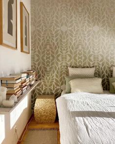 a white bed sitting in a bedroom next to a wall with pictures on top of it