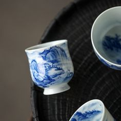 three blue and white cups sitting on top of a black tray next to each other