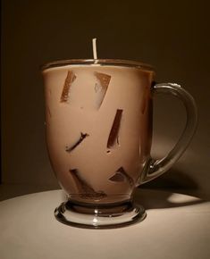 a coffee cup with a candle in it sitting on a table