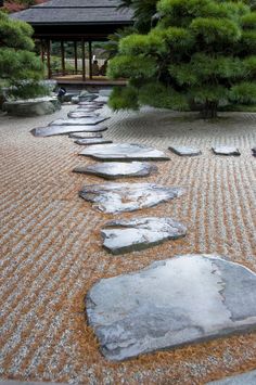 a stone path in the middle of a garden with rocks and gravel on it, leading to a gazebo