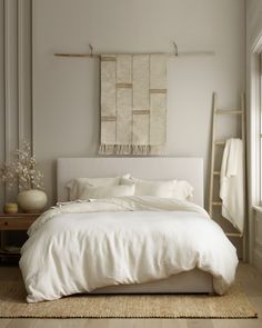 a white bed sitting in a bedroom next to a window