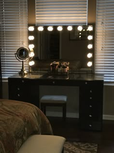 a vanity with lights on it in front of a mirror and bench next to a window