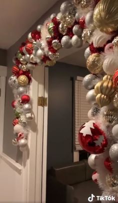 a decorated christmas tree with ornaments hanging from it's sides in front of a door