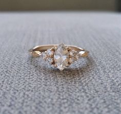 an engagement ring with three pear shaped diamonds on the side, sitting on top of a table